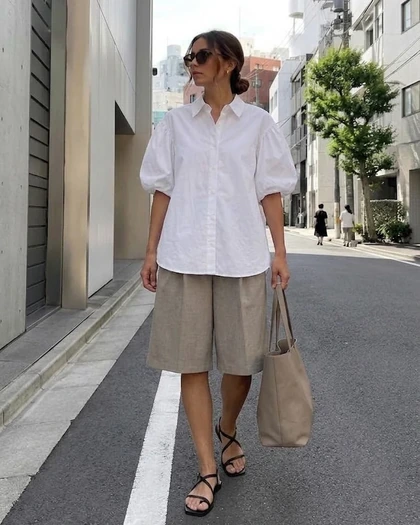 On-model photo of the white blouse and taupe shorts in the street